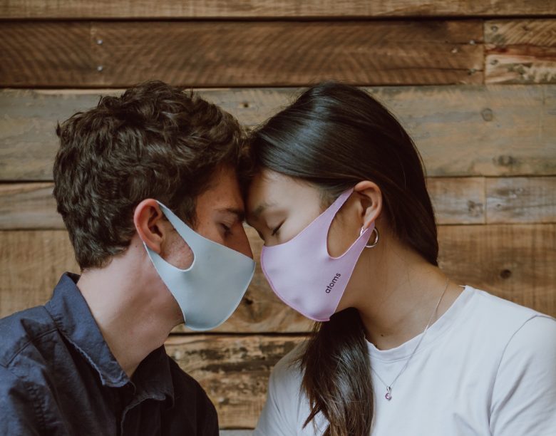 two people wearing masks touching foreheads for sexual health