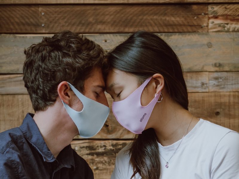 two people wearing masks touching foreheads for sexual health
