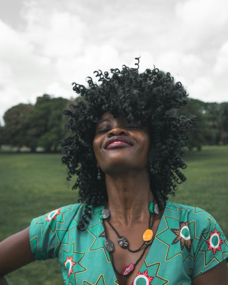 Black woman in a green dress flipping her hair