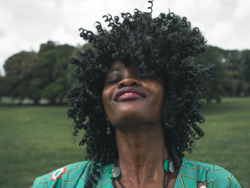 Black woman in a green dress flipping her hair