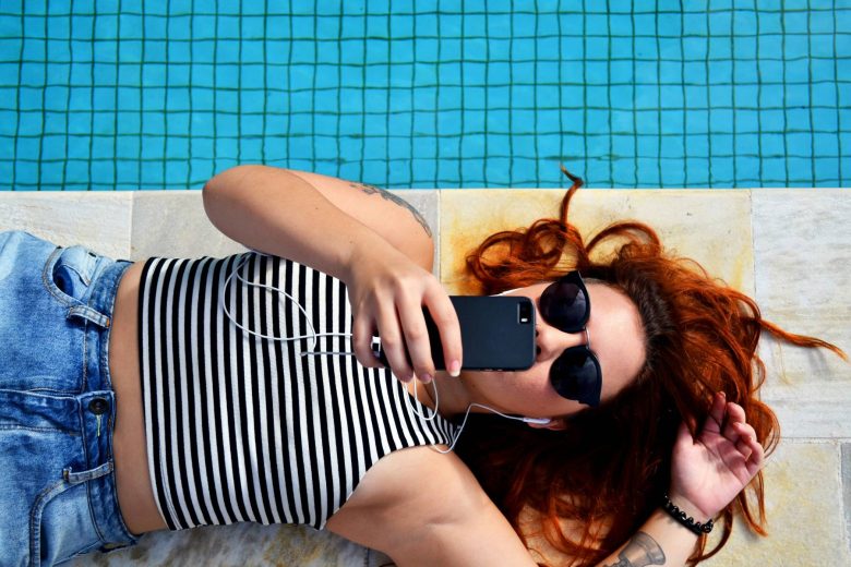 redheaded woman looking at her phone next to a pool for column on sext me