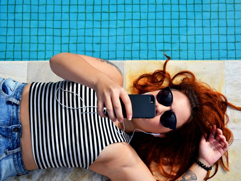 redheaded woman looking at her phone next to a pool for column on sext me